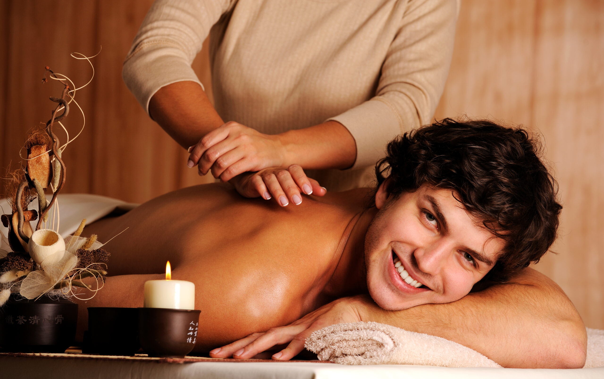 masseur doing massage a handsome happy young man